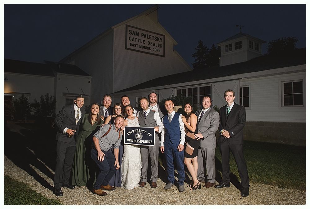 Group of people pose at night in front of a white building with a sign that reads 