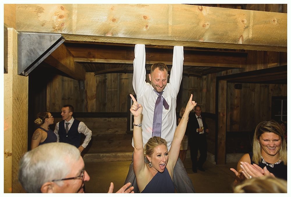 Man hanging from beam, woman cheering below, wedding reception setting.