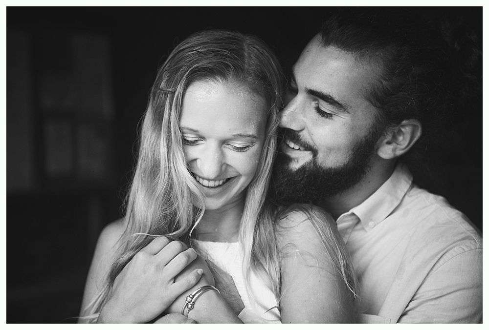 Woman smiling, embracing a man with a beard, intimate moment, black and white photo.