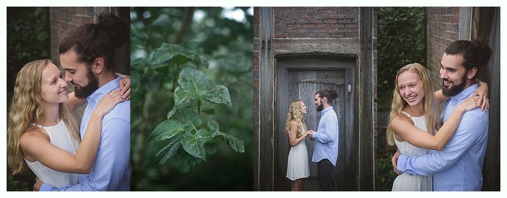Couple embraces. Woman in white dress, man with beard. Outdoor setting with greenery and wooden door.