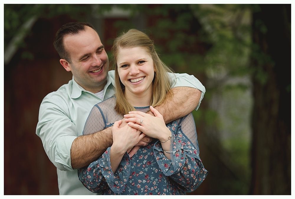 Bridesmaids in red dresses and shawls laugh with bride holding a bouquet outdoors.