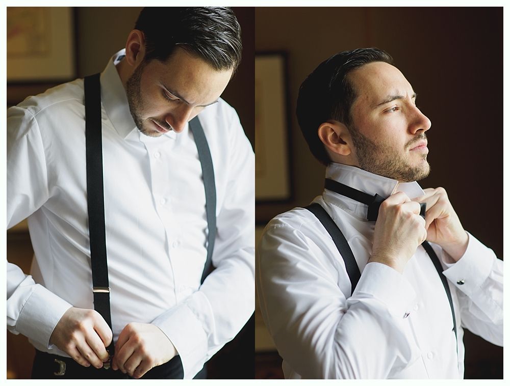 Man in white shirt and suspenders adjusting his attire in a well-lit room.