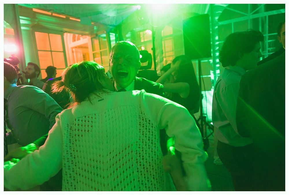 People dancing in a brightly lit room with green and orange lights.