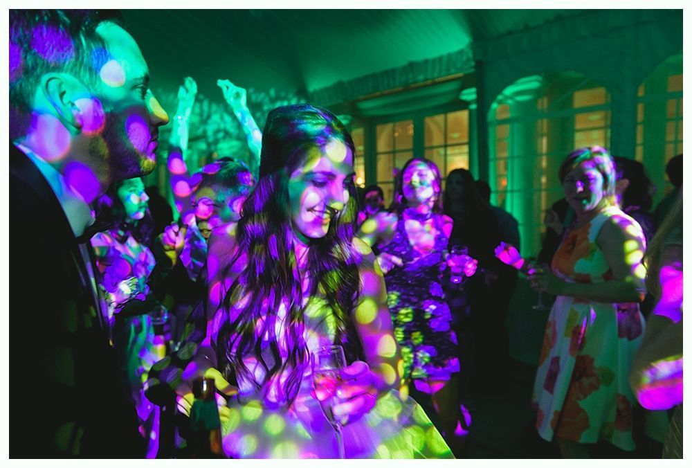 People dancing at a party with colorful spotlights.