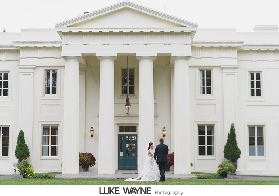 Bride and groom standing in front of a white building with pillars and a green door.