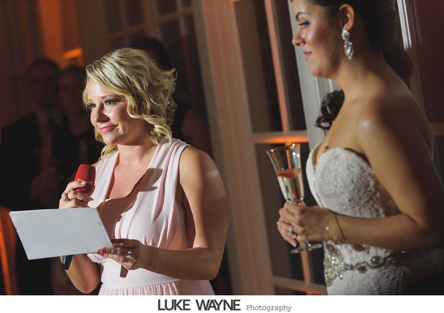 Woman giving speech, holding microphone and paper, bride with champagne glass.