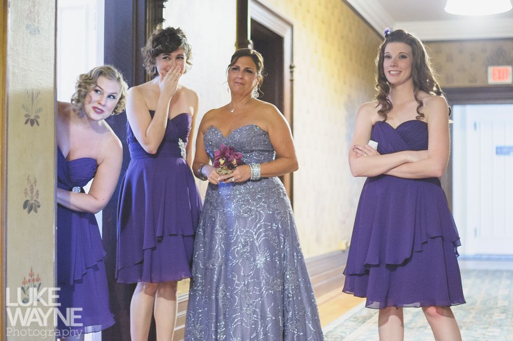Couple embracing on a rocky peak, with a tower in the background, under a cloudy sky.