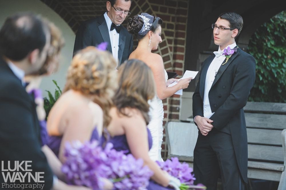 Couple embracing at sunset; man in green shirt, woman in denim jacket and red dress, with blowing hair.