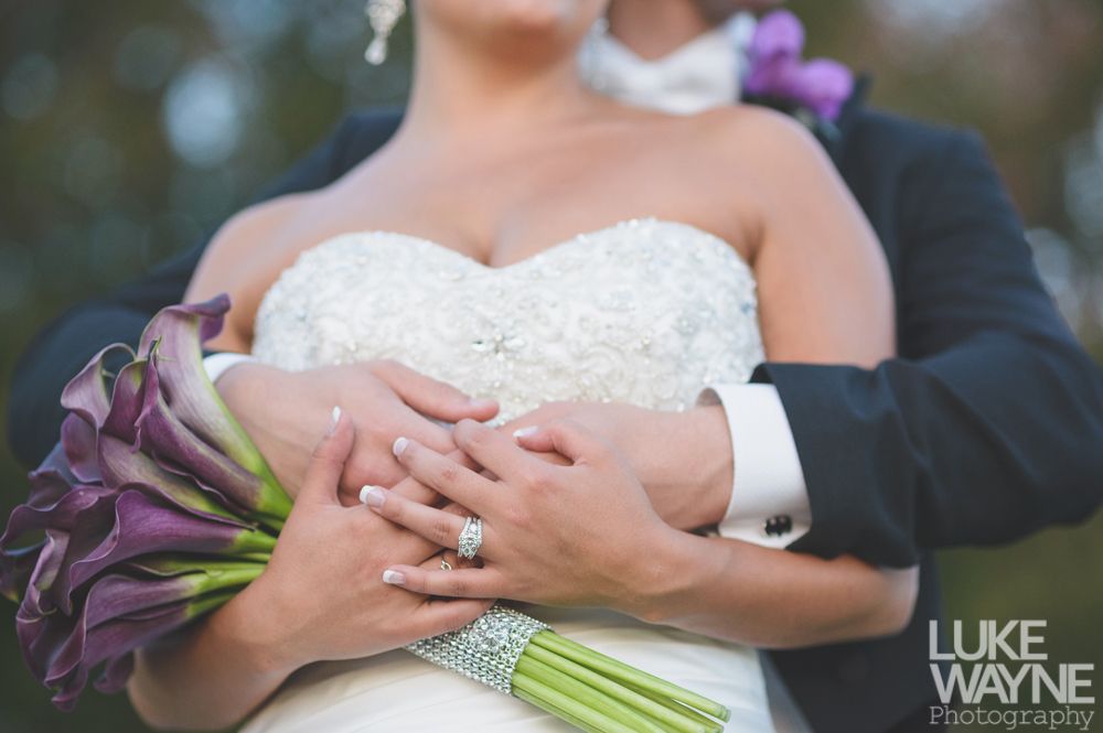 Couple embracing at sunset; man in green shirt, woman in denim jacket and red dress, with blowing hair.