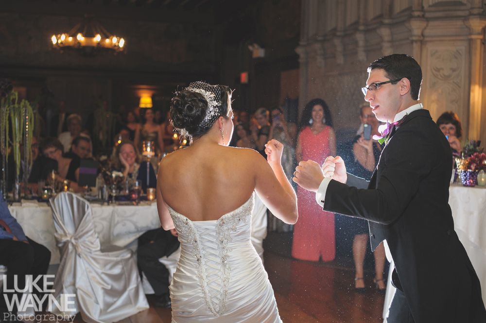 Couple embracing at sunset; man in green shirt, woman in denim jacket and red dress, with blowing hair.