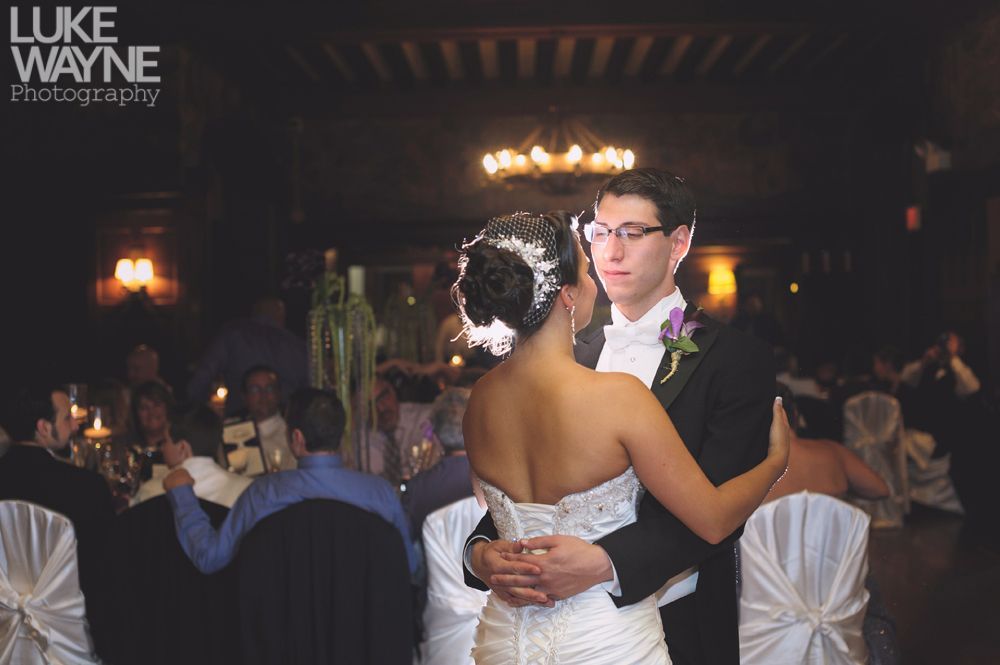 Couple embracing at sunset; man in green shirt, woman in denim jacket and red dress, with blowing hair.