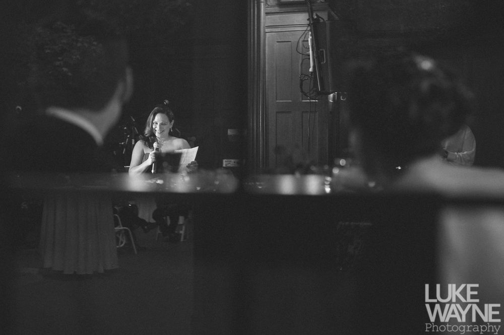 Couple embracing at sunset; man in green shirt, woman in denim jacket and red dress, with blowing hair.