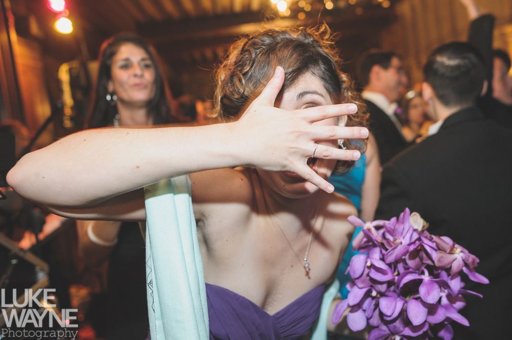 Couple embracing at sunset; man in green shirt, woman in denim jacket and red dress, with blowing hair.