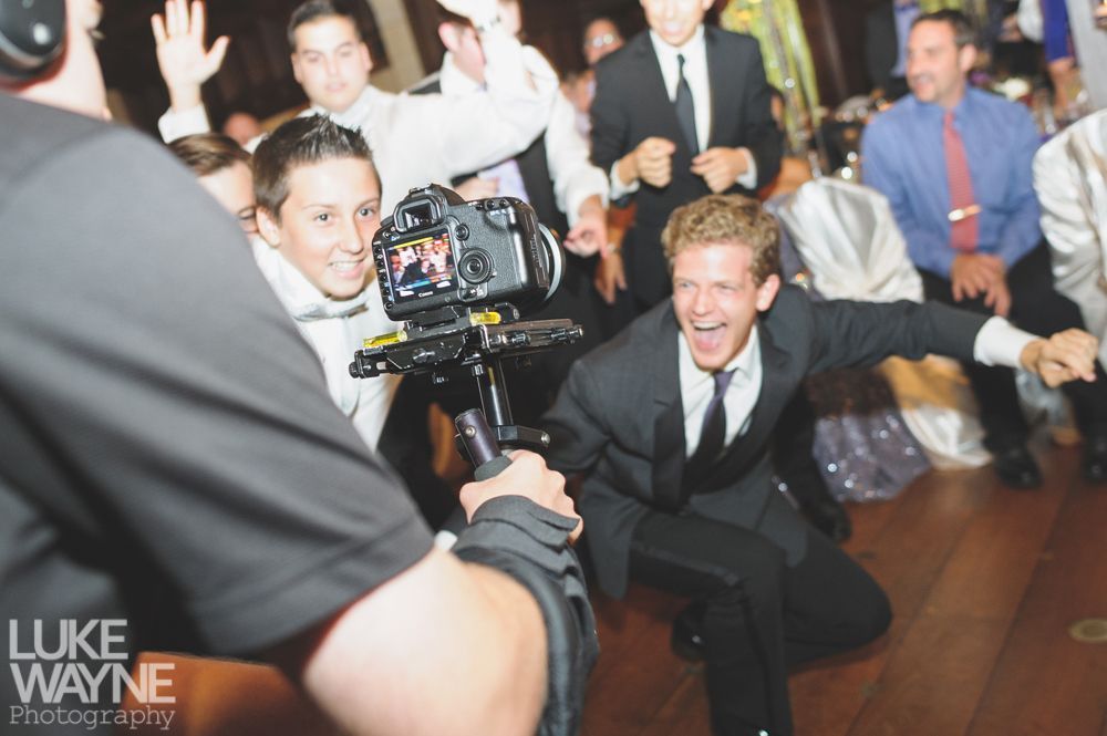 Couple embracing at sunset; man in green shirt, woman in denim jacket and red dress, with blowing hair.
