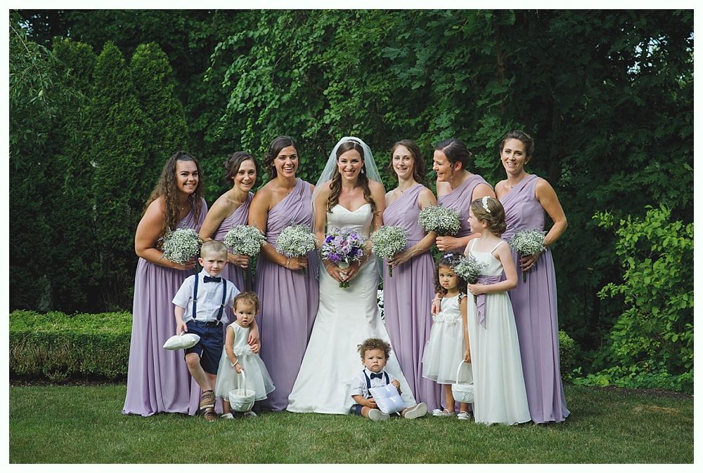 Bride with arms up, making a funny face, groom looking at his hand, cake cutting in background.