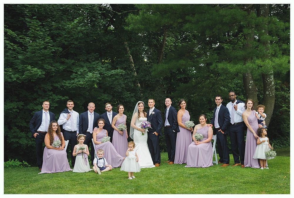 Bride with arms up, making a funny face, groom looking at his hand, cake cutting in background.