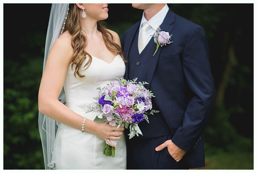 Bride with arms up, making a funny face, groom looking at his hand, cake cutting in background.