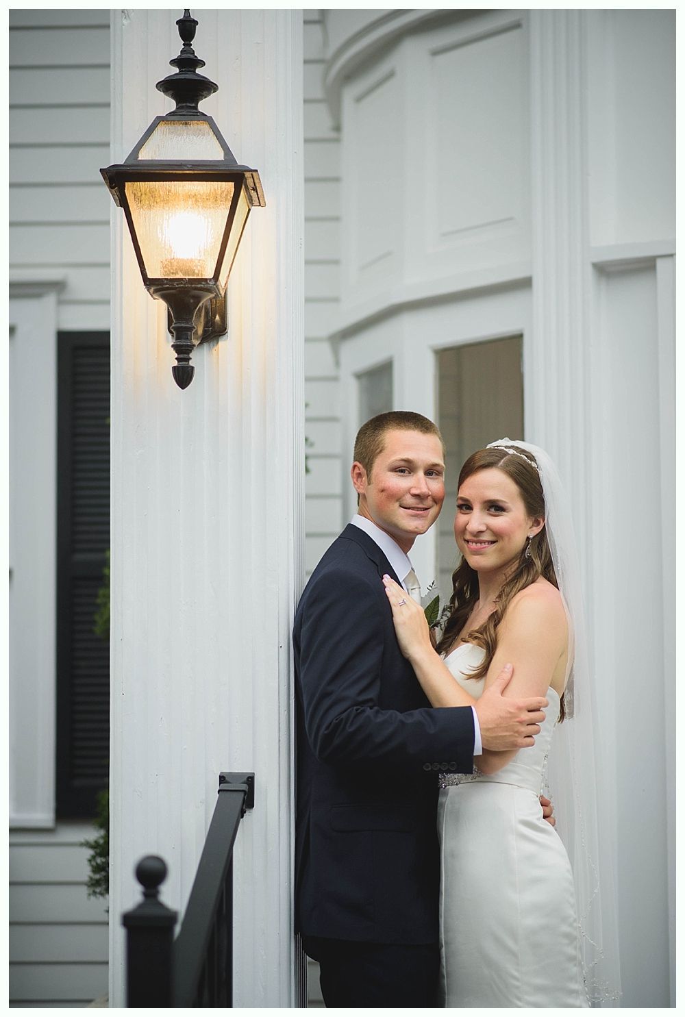 Bride with arms up, making a funny face, groom looking at his hand, cake cutting in background.