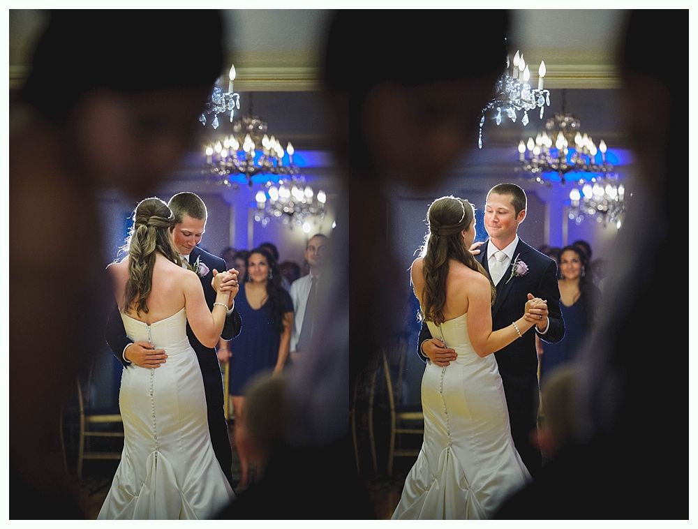 Bride with arms up, making a funny face, groom looking at his hand, cake cutting in background.