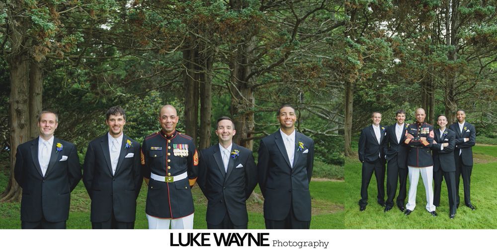 Groomsmen pose outdoors in front of trees. Some wear suits, while one man wears a military uniform.