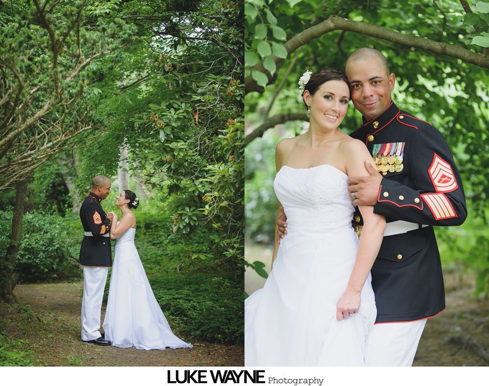 Bride and groom in wedding attire pose in a lush, green outdoor setting. The man wears a military uniform.