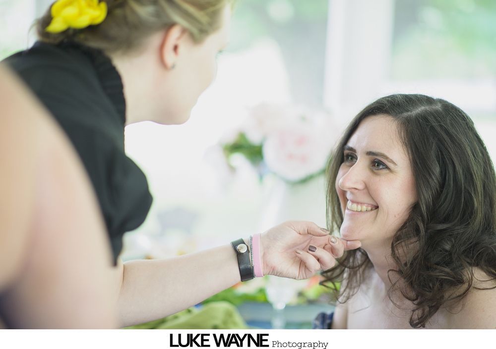 Man in gray suit with bow tie and boutonniere, smiling, outside near an old vehicle.