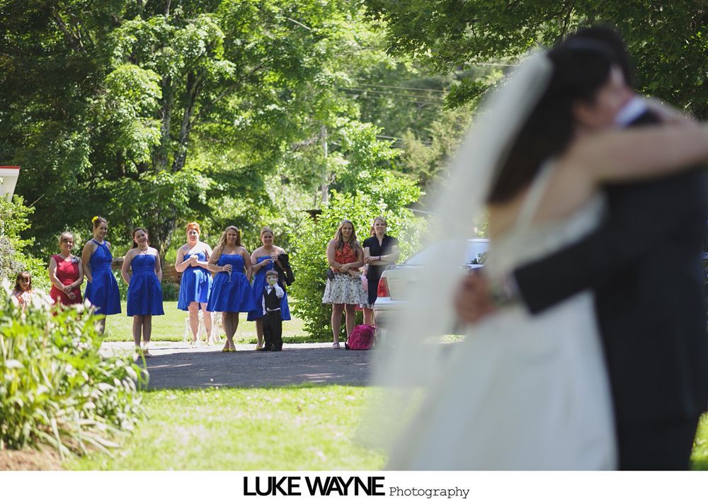 Bride walks down the aisle with her father at a wedding. Guests seated on either side of the aisle. Venue decorated with hanging lanterns.