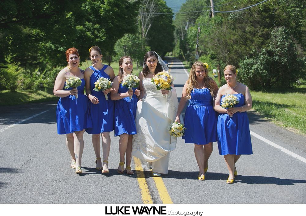 Newlyweds walking down the aisle after a wedding ceremony, guests clapping. Glass enclosed building, white paper lanterns overhead.