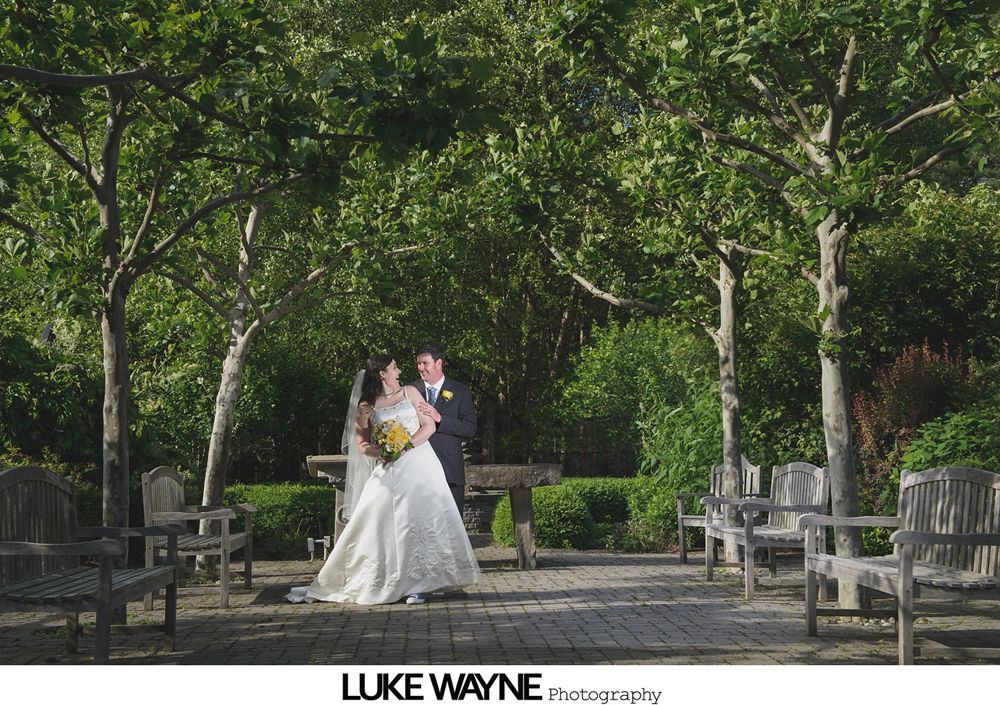 Bride and groom dance closely, illuminated by a back light, during a wedding reception.