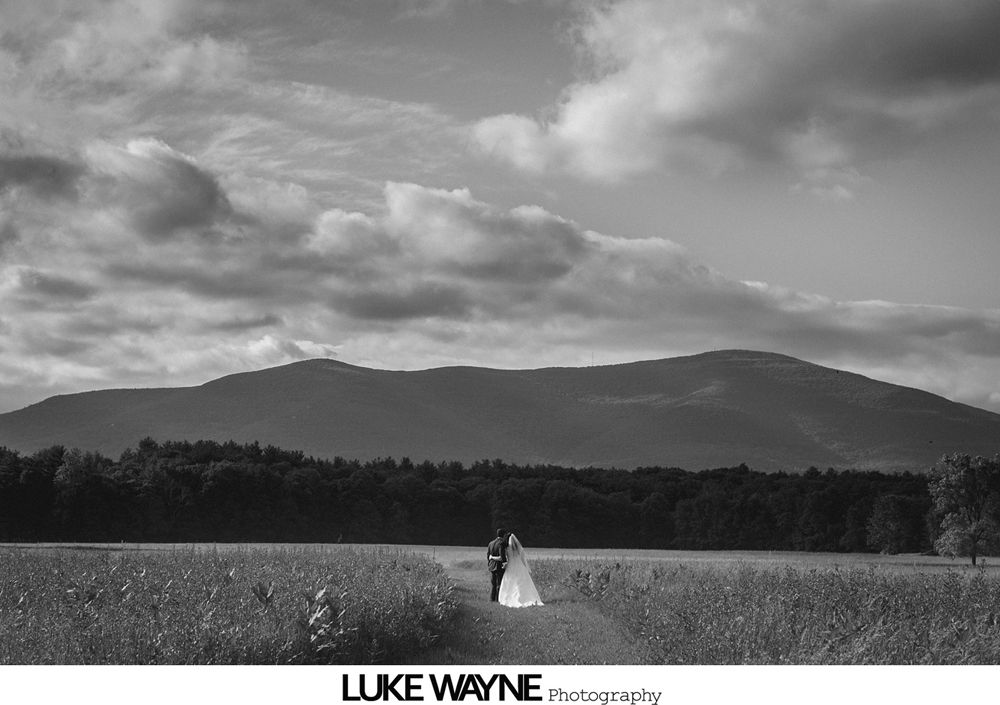 Wedding couple kissing under an umbrella in the rain.