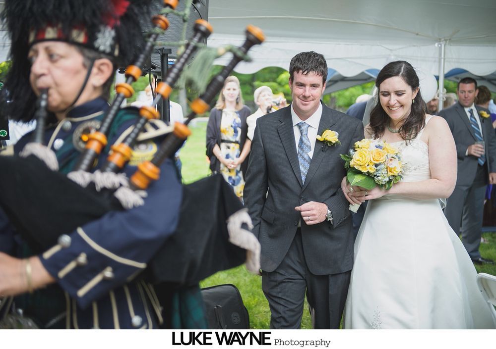 Group photo at a wedding reception. Bride and groom centered, surrounded by guests in formal attire.