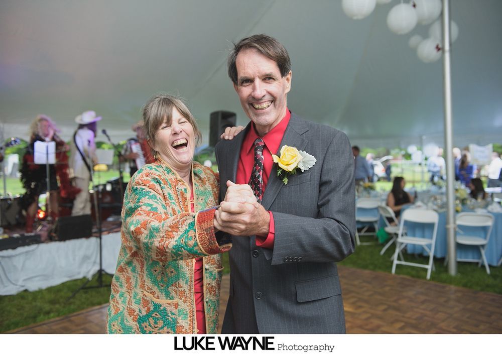 Group photo at a wedding reception. Bride and groom centered, surrounded by guests in formal attire.