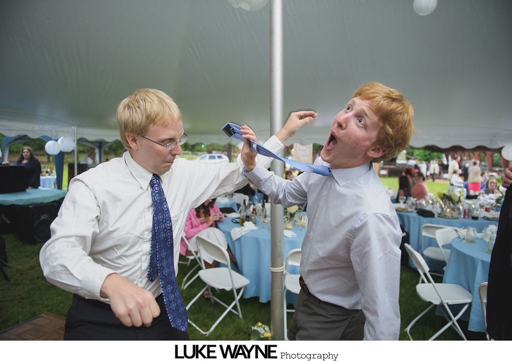 Group photo at a wedding reception. Bride and groom centered, surrounded by guests in formal attire.
