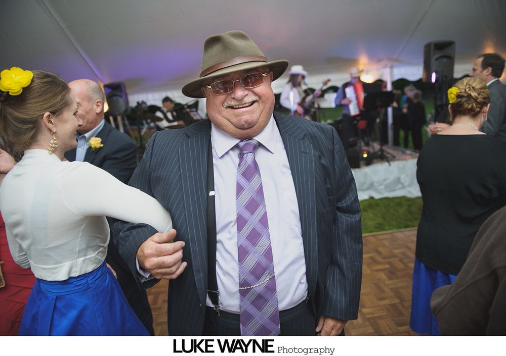 Group photo at a wedding reception. Bride and groom centered, surrounded by guests in formal attire.