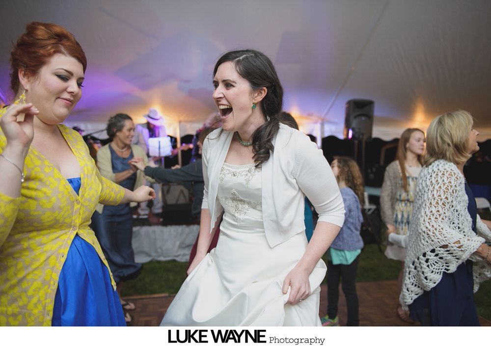 Group photo at a wedding reception. Bride and groom centered, surrounded by guests in formal attire.