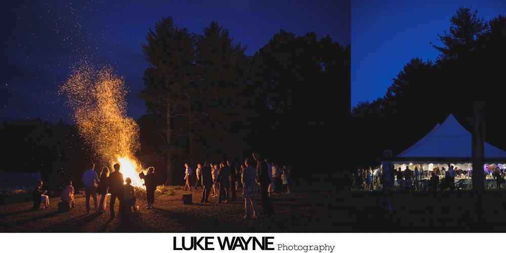 Group photo at a wedding reception. Bride and groom centered, surrounded by guests in formal attire.