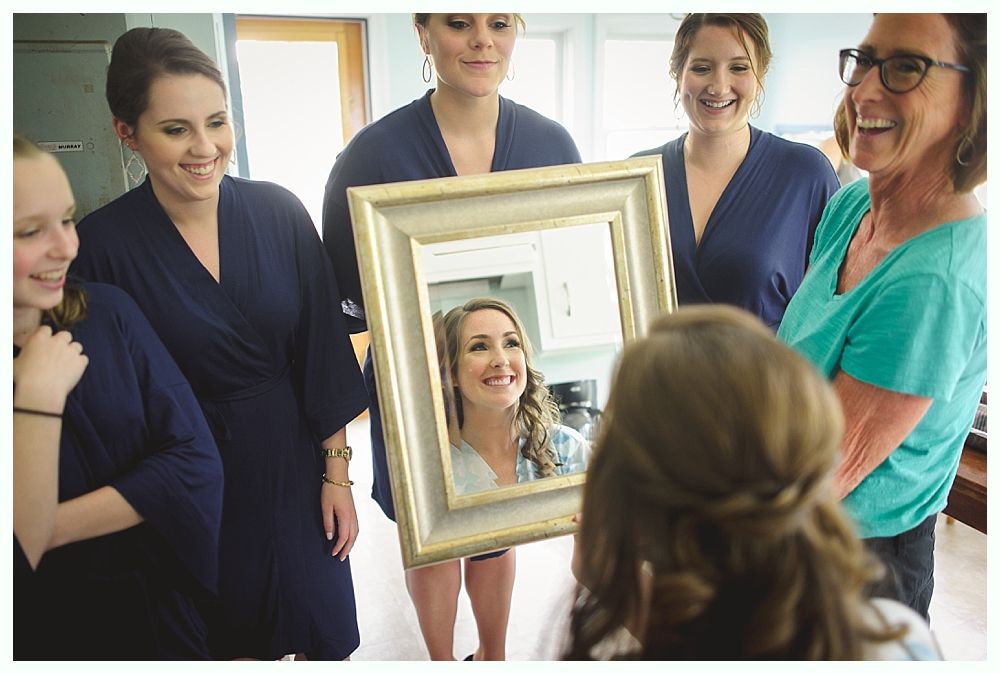 Woman having makeup applied with lip brush in warm-lit room, wearing floral robe.