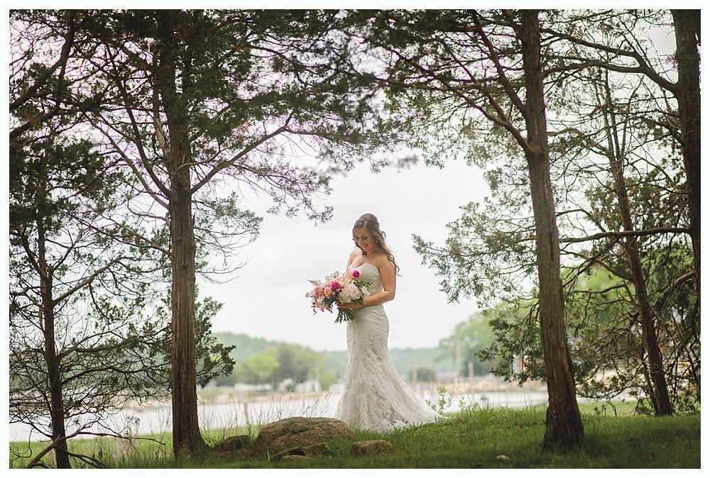 Hands clasped over a white wedding dress. A ring is visible on a finger.