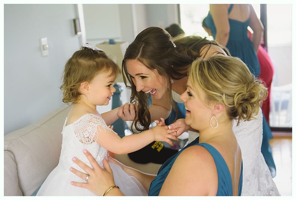 Bride and groom smiling, holding hands. Bride in white gown with veil, groom in gray suit, outdoors.