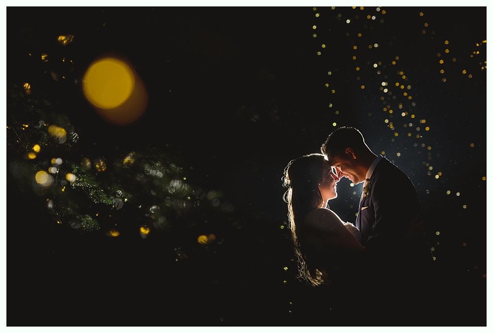 Bride embracing woman on dance floor at reception, surrounded by guests.