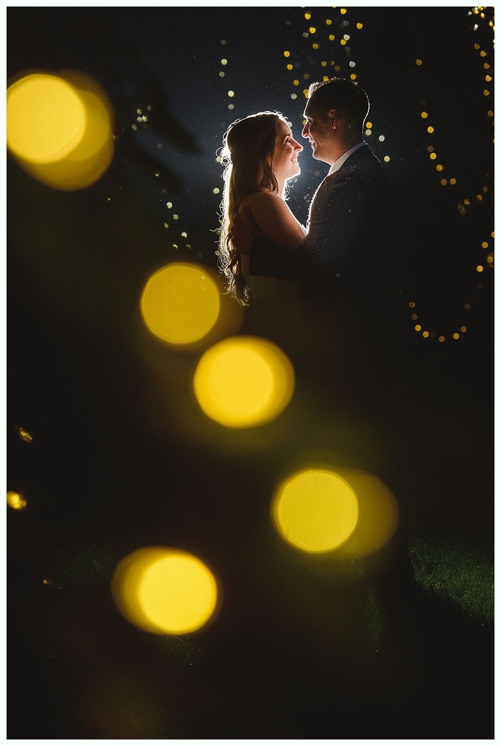 Groom jumps in excitement as bride bends backward during a wedding reception, many guests cheering.