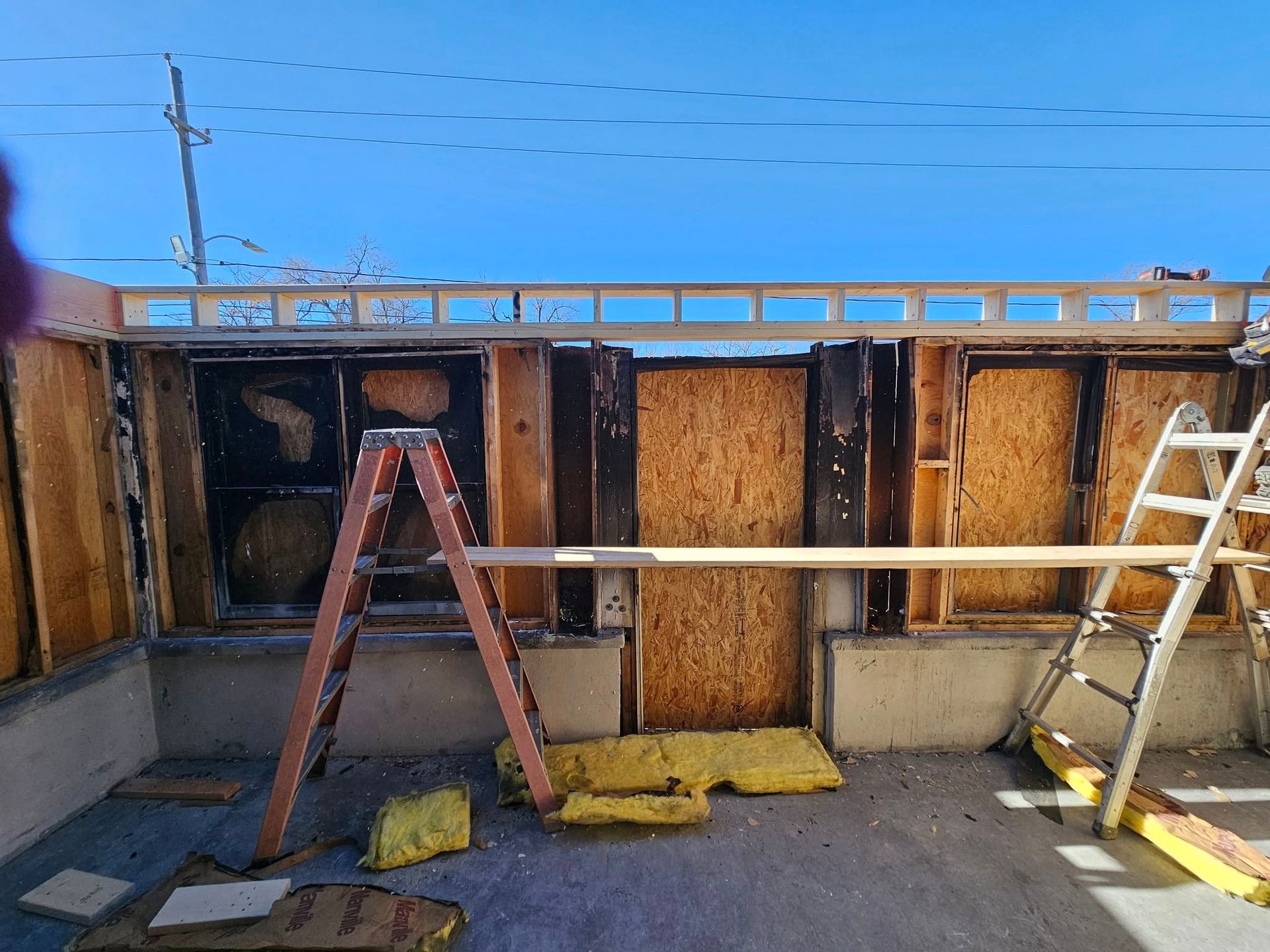 A ladder is sitting in front of a building under construction.