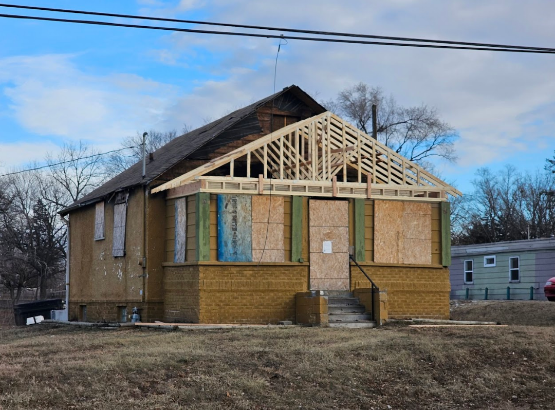 A house is being built in a field with a roof that is being built.