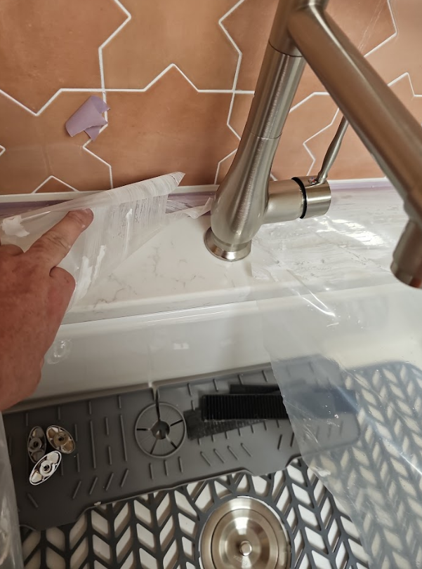 A person is holding a plastic bag over a sink faucet.