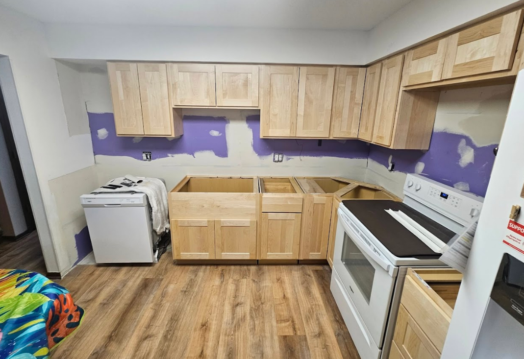 A kitchen with wooden cabinets , a stove , and a dishwasher.