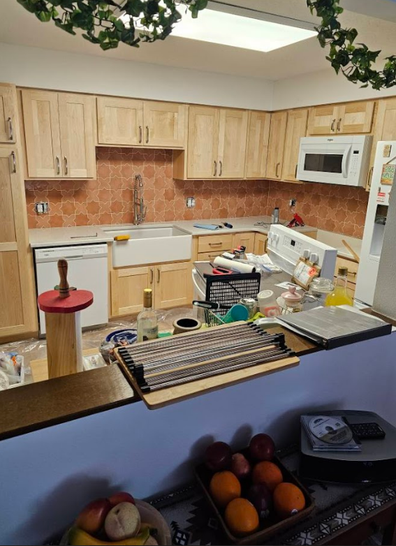 A kitchen with wooden cabinets , a sink , and a microwave.