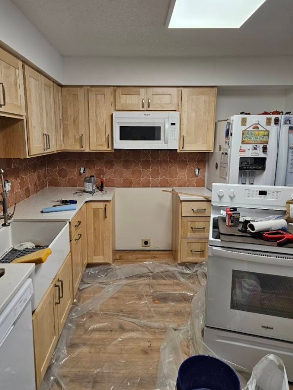 A kitchen with wooden cabinets , a stove , a microwave and a refrigerator.
