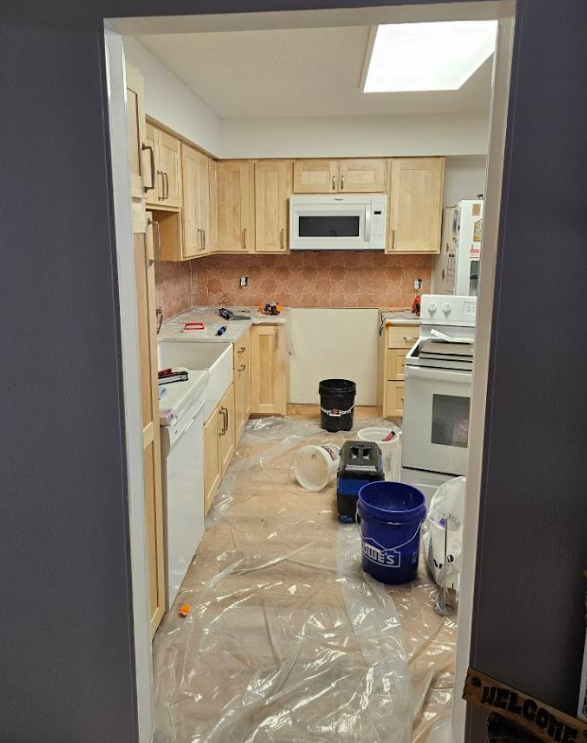 A kitchen with wooden cabinets , a stove , and a microwave.