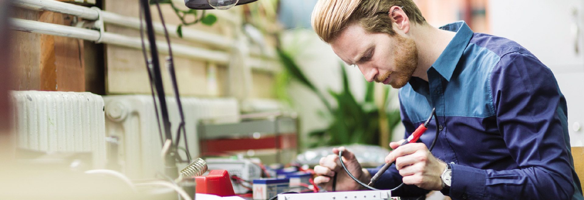 A man is working on an electronic device in a lab.