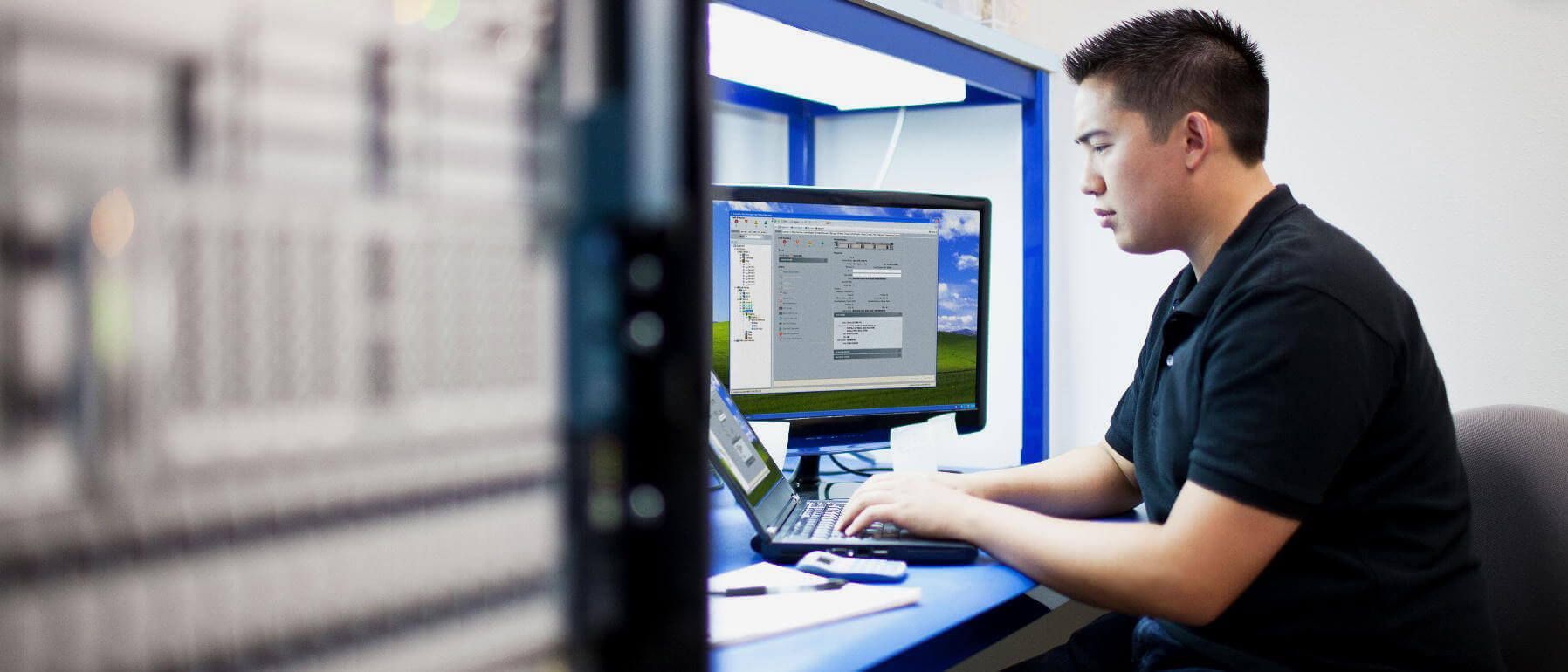 A man is sitting at a desk using a laptop computer.
